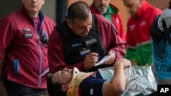 A police officer talks to a commuter who was injured when two trains collided in Buenos Aires, Argentina, May 10, 2024.