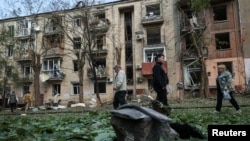 Local residents walk near an apartment building damaged by a Russian airstrike in Kharkiv, Ukraine, May 5, 2024.