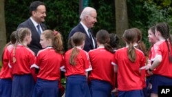 U.S. President Joe Biden and Ireland's Taoiseach Leo Varadkar talk with children after watching a youth Gaelic sports demonstration at Farmleigh House, April 13, 2023, in Dublin.