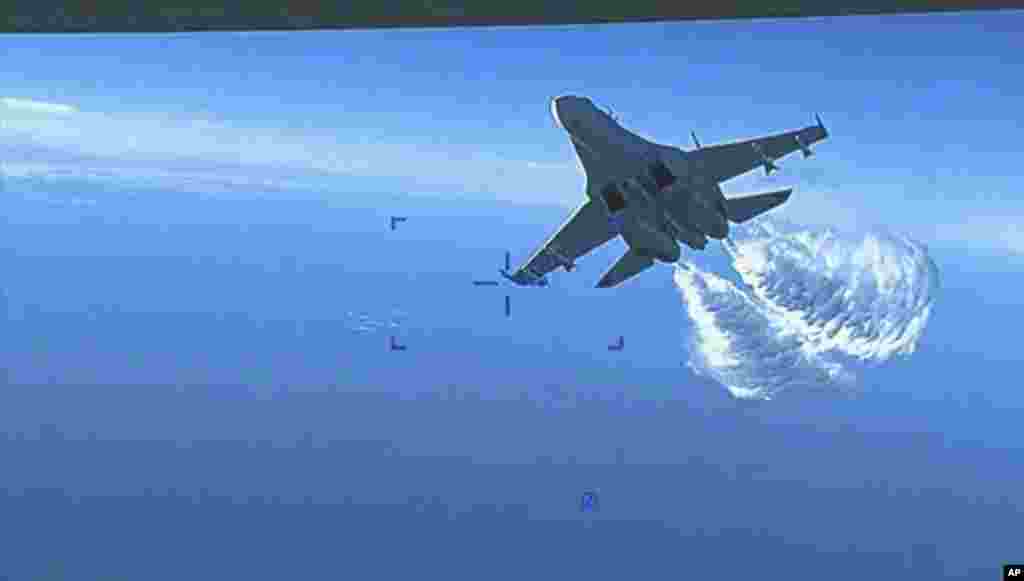 This photo taken from video shows a Russian Su-27 approaching the back of the MQ-9 drone and beginning to release fuel as it passes, over the Black Sea, the Pentagon said. (U.S. Department of Defense via AP)