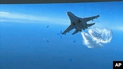 This photo taken from video released March 16, 2023, shows a Russian Su-27 approaching the back of the MQ-9 drone and beginning to release fuel as it passes, over the Black Sea, the Pentagon said. 