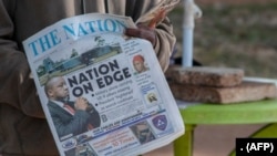 在马拉维首都利隆圭的街头，一名报贩举着在头版头条报道副总统奇利马飞机失联消息的《民族报》。(2024年6月11日)