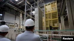 FILE - People stand next to the production line inside the gigafactory of Automotive Cells Company (ACC), a joint venture of Stellantis, TotalEnergies and Mercedes, during its inauguration in Billy-Berclau-Douvrin, northern France, May 30, 2023.