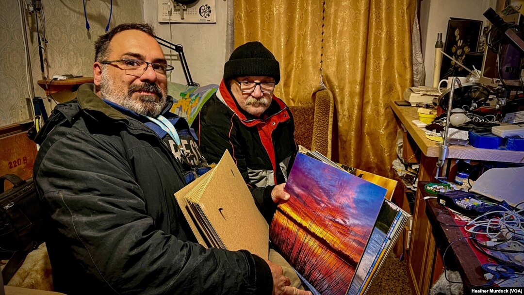 Yan Boechat (L) and Aleksandr Petrenko (R) flip through Petrenko's photos on Jan. 26, 2023 in Kherson, Ukraine.