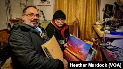 Yan Boechat (L) and Aleksandr Petrenko (R) flip through Petrenko's photos on Jan. 26, 2023 in Kherson, Ukraine.