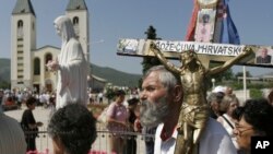 FILE - Pilgrims walk around a statue of the Blessed Virgin Mary near the church of St. James in Medjugorje, Bosnia and Herzegovina, June 25, 2006.