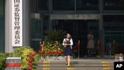 FILE - A woman walks out of the China Securities Regulatory Commission on Financial Street in Beijing, July 9, 2015.