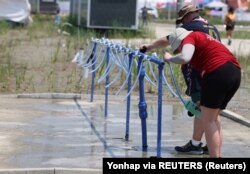 Peserta Jambore Pramuka Dunia ke-25 mengisi botol-botol air di zona persediaan air tempat perkemahan di Buan, Korea Selatan, 2 Agustus 2023. (Foto: Yonhap via REUTERS)