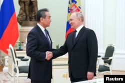 Presiden Rusia Vladimir Putin berjabat tangan dengan Menteri Luar Negeri China Wang Yi di Moskow, Rusia, 22 Februari 2023. (Foto: Sputnik/Anton Novoderezhkin via REUTERS)