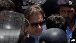 Mantan Perdana Menteri Pakistan Imran Khan, tengah, dikawal oleh petugas polisi saat dia tiba untuk menghadiri pengadilan, di Islamabad, Pakistan, Jumat, 12 Mei 2023. (AP/Anjum Naveed)