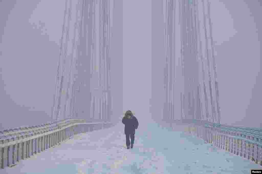 Човек оди по мостот Виноградовски преку реката Јенисеј, додека температурата на воздухот се спушта на минус 35 целзиусови степени, во сибирскиот град Краснојарск, Русија.