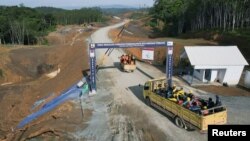 Para pekerja mengendarai truk memasuki kawasan inti pemerintahan di Ibu Kota Negara Nusantara (IKN), di Sepaku, Kalimantan Timur, 8 Maret 2023. (Foto: REUTERS/Willy Kurniawan)