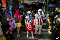 Para pengunjung mengenakan kostum Mandalorian Captain America berpose di acara New York Comic Con di Jacob K. Javits Convention Center, Jumat, 13 Oktober 2023, di New York. (Charles Sykes/Invision/AP)