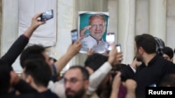 Poster yang menampilkan wajah presiden Iran yang baru terpilih, Masoud Pezeshkian, dibawa oleh pendukungnya ketika berkumpul di sebuah area di dekat Teheran, Iran, pada 6 Juli 2024. (Majid Asgaripour/West Asia News Agency via Reuters)