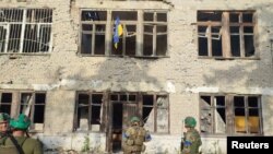 Ukrainian soldiers stand under a Ukrainian flag during an operation that claims to liberate a village named as Blahodatne, Donetsk Region, Ukraine, in this screengrab from a handout video released June 11, 2023. (68th Separate Hunting Brigade 'Oleksy Dovbusha'/via Reuters)