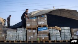 A man unloads humanitarian aid on a convoy of lorries entering the Gaza Strip from Egypt via the Rafah border crossing, Oct. 21, 2023. 