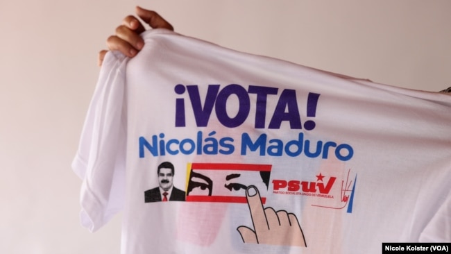 Sandoval sostiene una franela con propaganda a favor de Maduro, que quiere proyectarse a 18 años en el poder