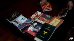 Peugas kepolisian federal Argentina menunjukkan buku-buku bertema Nazi yang disita dalam konferensi pers di Buenos Aires, Argentina, pada 13 September 2023. (Foto: AP/Natacha Pisarenko)