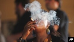 FILE — An unidentified woman smokes Marijuana at the New Afrika Shrine in Lagos, on February 6, 2011.