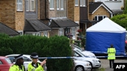 Sejumlah polisi berjaga di dekat tenda tim forensik yang didirikan di wilayah Ashley Close di Bushey, di utara London, pada 10 Juli 2024, menyusul kasus pembunuhan "crossbow" yang terjadi di wilayah tersebut. (Foto: AFP/Justin Tallis)