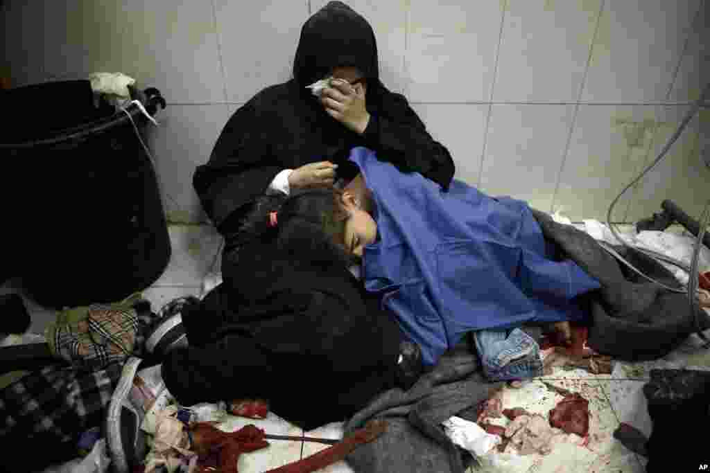A Palestinian woman cries as she sits next to her girl wounded in the Israeli bombardment of the Gaza Strip while receiving treatment at the Nasser hospital in Khan Younis, Southern Gaza Strip.