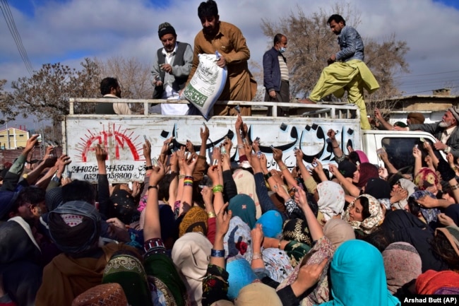 FILE - People crowd each other to buy subsidized sacks of wheat flour in Quetta, Pakistan, Thursday, Jan. 12, 2023, after a recent price increase of flour in the country. (AP Photo/Arshad Butt, File)