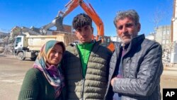 Taha Erdem, 17; his mother, Zeliha Erdem, and father Ali Erdem pose for a photograph next to the destroyed building where Tahan was trapped after the earthquake of Feb. 6, in Adiyaman, Turkey, Feb. 17, 2023.