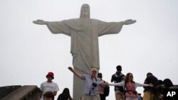 Turistas posan para fotos frente a la estatua del Cristo Redentor durante un día de niebla en Río de Janeiro, Brasil, el 17 de marzo de 2020.
