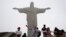 Turistas posan para fotos frente a la estatua del Cristo Redentor durante un día de niebla en Río de Janeiro, Brasil, el 17 de marzo de 2020.
