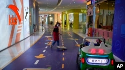 北京一家商场的工人在一家玩具商店外清洁地板。（2023年4月4日）