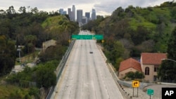 FILE - Extremely light traffic moves along the 110 Harbor Freeway toward downtown Los Angeles in the mid-afternoon of March 20, 2020.