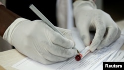 FILE - A doctor registers blood after testing a patient at a local government hospital in Harare, Zimbabwe, Feb. 4, 2020