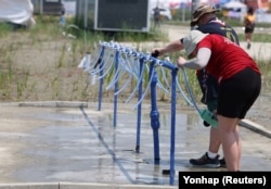 Participants for the 25th World Scout Jamboree fill water bottles at a water supply zone of a camping site in Buan, South Korea, Aug. 2, 2023. (Yonhap via Reuters)