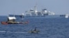 资料照：一艘中国海警船在南中国海有争议的海域监视菲律宾渔民的木船。（2024年5月16日 ）