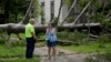 A resident of Bay City Texas, right, talks with a city worker as she stands in front of her neighbor's home after Beryl passed through on July 8, 2024.