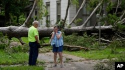 A resident of Bay City Texas, right, talks with a city worker as she stands in front of her neighbor's home after Beryl passed through on July 8, 2024.