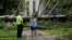 A resident of Bay City Texas, right, talks with a city worker as she stands in front of her neighbor's home after Beryl passed through on July 8, 2024.