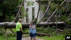 FILE - A resident of Bay City Texas, right, talks with a city worker as she stands in front of her neighbor's home after Beryl passed through on July 8, 2024.