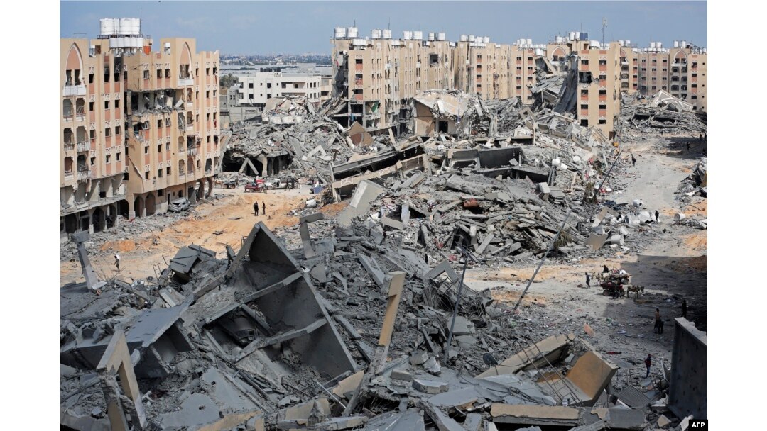 Pengungsi Palestina berjalan di tengah puing-puing rumah yang hancur akibat pemboman Israel di kawasan Hamad, sebelah barat Khan Yunis di selatan Jalur Gaza, 14 Maret 2024. (Foto: AFP)