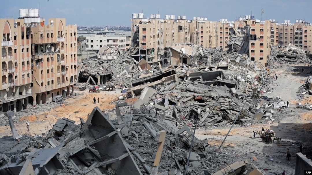 Pengungsi Palestina berjalan di tengah puing-puing rumah yang hancur akibat pemboman Israel di kawasan Hamad, sebelah barat Khan Yunis di Jalur Gaza selatan, 14 Maret 2024.