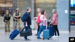 Commuters walk past New York National Guard soldiers standing guard at Penn Station, March 7, 2024, in New York.