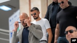 Andrew Tate, left, leaves the Bucharest Tribunal along with his bodyguards after appearing in court, in Romania, June 21, 2023.