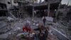 The Palestinian Al-Naji family prepares to break their fast during the first day of the Muslim holy fasting month of Ramadan sitting amidst the ruins of their family house in Deir el-Balah, central Gaza Strip, March 11, 2024