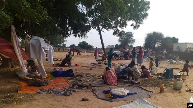 FILE - Residents displaced from a surge of violent attacks squat on blankets and in hastily made tents in the village of Masteri in west Darfur, Sudan, on July 30, 2020.