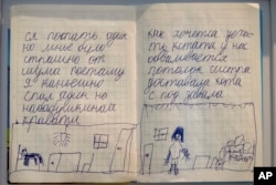 Two pages of the diary of Yehor Kravtsov, 10 years-old, are exhibited at the War Diaries exhibition, showcasing the personal diaries of Ukrainian children who have witnessed the war. (AP Photo/Peter Dejong)