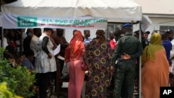 FILE - People queue to collect their elections permanent voters cards at a distribution center.