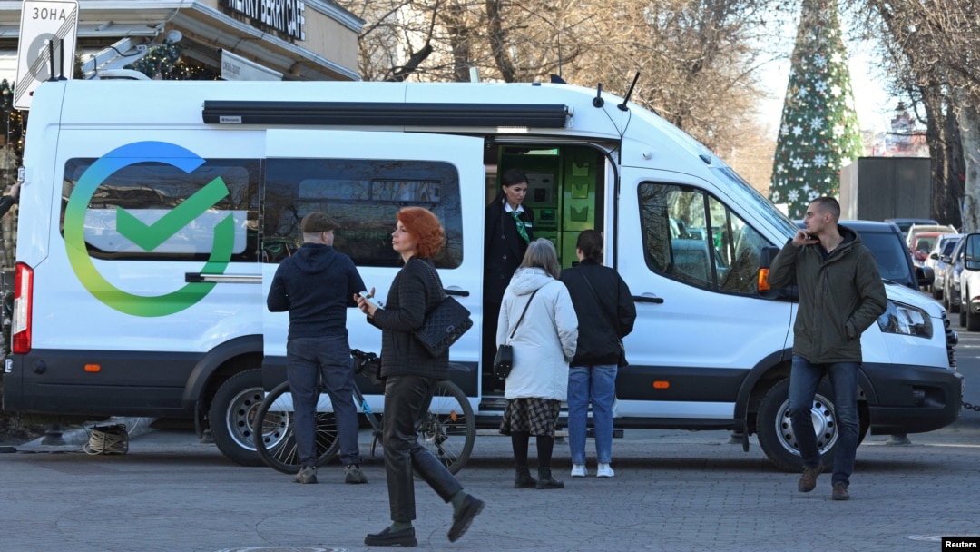 FILE: Para nasabah berbicara dengan pegawai bank di kantor keliling Sberbank di Simferopol, Krimea, 21 Januari 2023. (REUTERS/Alexey Pavlishak)