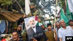 Demonstran mengibarkan bendera dan memegang foto pemimpin kelompok militan Palestina Hamas, Ismail Haniyeh, (tengah) dan pemimpin senior Saleh al-Arouri dalam aksi protes di kamp pengungsi Palestina Burj al-Barajneh di Beirut, pada 31 Juli 2024. (Fadel ITANI / AFP)