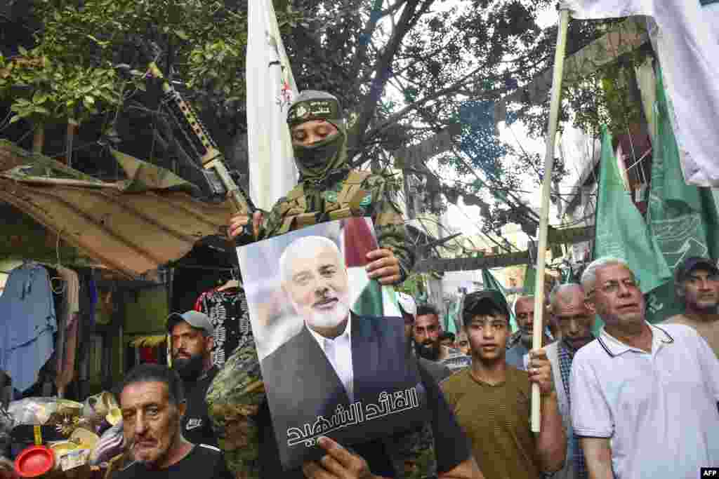 Para demonstran melambaikan bendera dan memegang gambar pemimpin kelompok militan Palestina Hamas, Ismail Haniyeh, selama aksi protes di kamp Burj al-Barajneh untuk pengungsi Palestina di Beirut, Lebanon. (AFP)&nbsp;