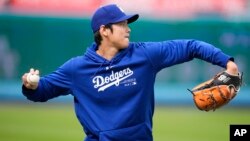 The Los Angeles Dodgers' Shohei Ohtani warms up on the field before the team's spring training baseball game against the Los Angeles Angels, March 25, 2024, in Los Angeles. 